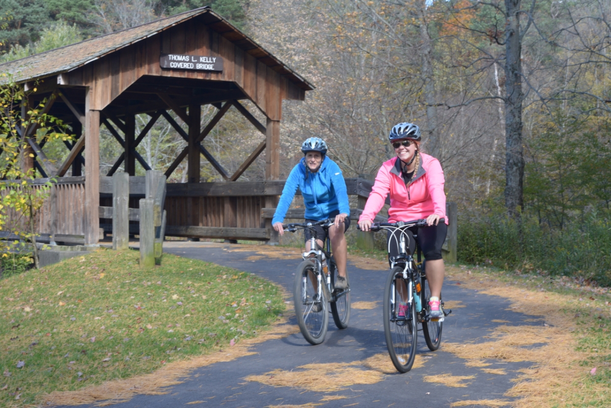 Ladies riding bicycles on paved bike trail at Allegany State Park
